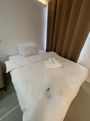 a white bed with two towels and a thermometer on it at Makati City Antel Spa Residences 9B in Manila