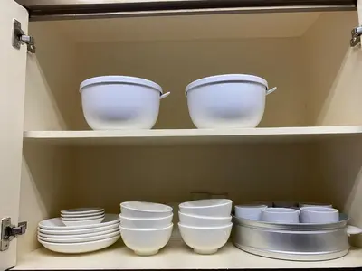 a shelf with white bowls and plates in a kitchen at Peaceful Port Away From Home in Manila