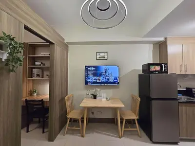 a kitchen with a table and a black refrigerator at 1BR Condotel with Balcony at FAME Residences #FM38-1 in Manila