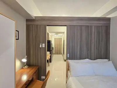a bedroom with a bed and a wooden headboard at 1BR Condotel with Balcony at FAME Residences #FM48-1 in Manila