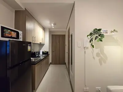 a kitchen with a black refrigerator and a sink at 1BR Condotel with Balcony at FAME Residences #FM57-1 in Manila