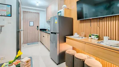 a kitchen with a refrigerator and a counter with stools at MOA Staycation at Shore 2 Residences Tower 3 in Manila