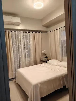 a bedroom with a bed with white sheets and curtains at Zenys Staycation at Shore 1 Residences in Manila