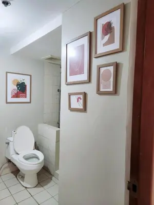 a bathroom with a toilet and pictures on the wall at 2BR 90sqm Furnished Condo Shaw Blvd, Mandaluyong in Manila