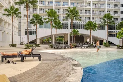 a man laying on a bench next to a swimming pool at Hotel Like Staycation Near Airport and MOA Porongs Oasis in Manila