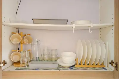a shelf with plates and other kitchen utensils at Hotel Like Staycation Near Airport and MOA Porongs Oasis in Manila