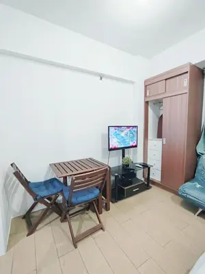 a living room with a table and a chair and a tv at Rose150newportpasay in Manila