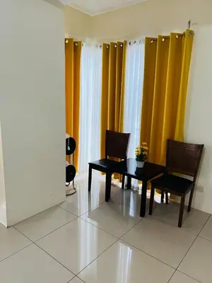 a dining room with yellow curtains and a table and chairs at Unit 958 B Shell Residences 2br in Manila