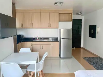 a kitchen with a white table and a white refrigerator at Avant at the Fort 360 City Center views in BGC Taguig w Pool Access in Manila