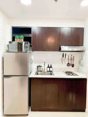 a kitchen with wooden cabinets and a stainless steel refrigerator at 2BR Condo w Pool Loft at Fort Victoria BGC Taguig in Manila