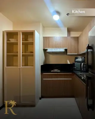 a kitchen with wooden cabinets and a black counter top at The Radiance Manila Bay - DF Sy 19J in Manila