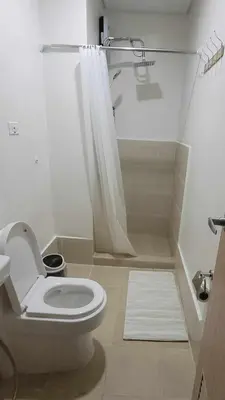 a white bathroom with a toilet and a shower at Leaf residences condotel 2bedroom Muntinlupa in Manila