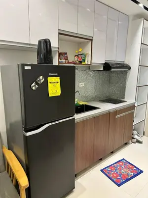 a kitchen with a black refrigerator with a yellow sticker on it at Cozy Condo at South Residences in Manila