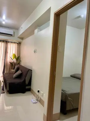 a bedroom with a mirror and a bed and a couch at comfy 1 bedroom family condo in Manila