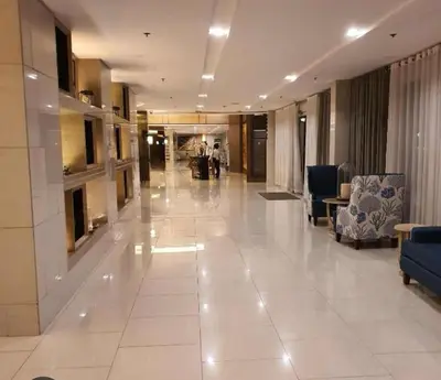 a large lobby with white tile floors and blue chairs at Shell Residences Family Suites 2 in Manila