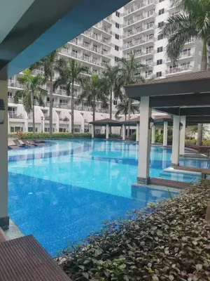 a large swimming pool with palm trees and a large building at Shell Residences Family Suites 2 in Manila