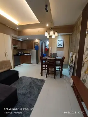 a living room with a table and a kitchen at 1 Bedroom Red Oak Serendra BGC in Manila