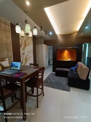 a living room with a table with a laptop on it at 1 Bedroom Red Oak Serendra BGC in Manila