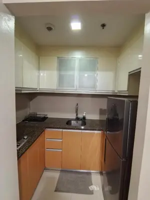 a kitchen with wooden cabinets and a stainless steel refrigerator at Classy Condotel Across NAIA Terminal 3 in Manila