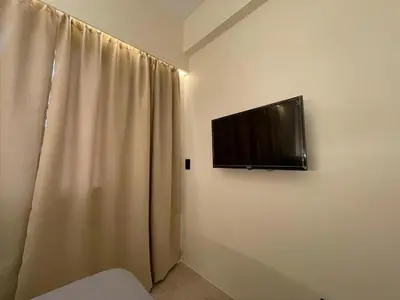 a television hanging on a wall next to a curtain at Pinecrest residential resort in Manila
