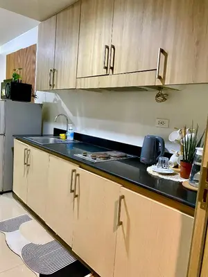 a kitchen with wooden cabinets and a black counter top at Shore Escape PH in Manila