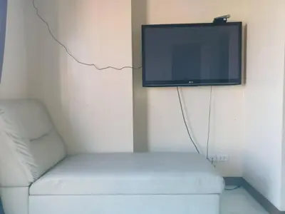 a living room with a white couch and a flat screen tv at Peaceful City View Condo for Rent in Quezon City in Manila