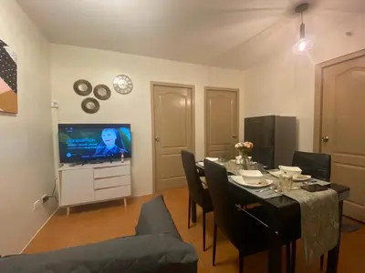 a dining room with a table and a television at Escapade Home in Manila