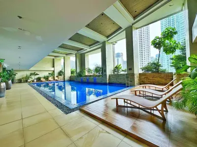 a pool in a building with two chairs in the middle at Private Unit at KL Tower Residences near Greenbelt Makati in Manila
