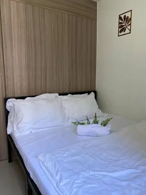 a bed with white sheets and plants on it at AJ Staycation Shore 2 in Manila