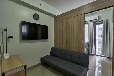 a living room with a couch and a tv on the wall at MOA Shorescape City Life with WiFi in Manila