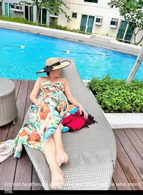 a woman sitting on a chair next to a pool at Phebs 2bedroom Posh Condo in the heart of Makati in Manila