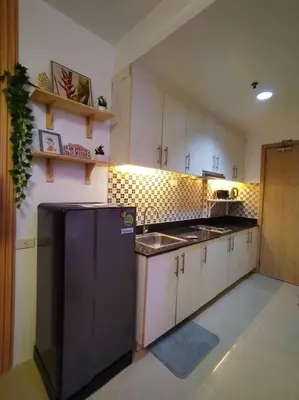 a kitchen with white cabinets and a black refrigerator at Sea Residences - MOA in Manila