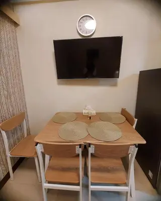 a wooden table with chairs and a clock on a wall at Field Residences by Diane in Manila