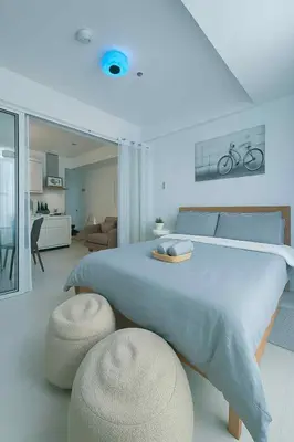 a white bedroom with a large bed and two stools at Golden Hour Escape in Manila
