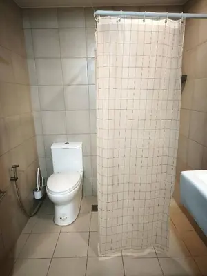 a bathroom with a toilet and a shower curtain at Modern Studio Condo in Heart of Quezon City in Manila
