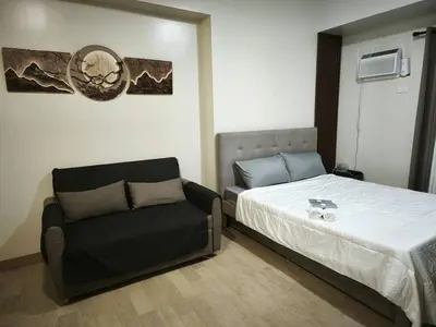 a bedroom with a bed and a chair at Modern Studio Condo in Heart of Quezon City in Manila