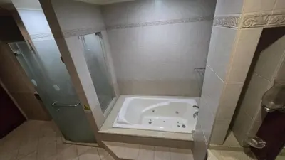 a bath tub in a bathroom with a shower at Hassan Sisters' EnSuites in Manila