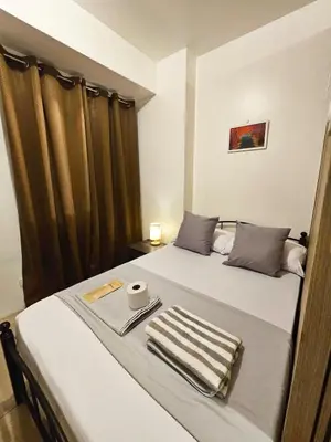 a hotel room with two beds with curtains and a towel at Cozy 1BR beside MOA with Wifi, Netflix, Pool & Washer in Manila