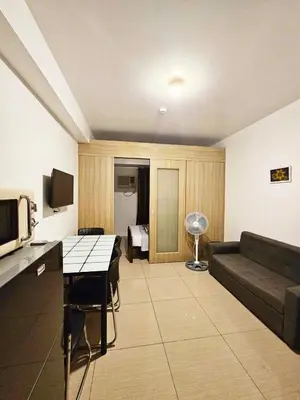 a living room with a couch and a table at Cozy 1BR beside MOA with Wifi, Netflix, Pool & Washer in Manila