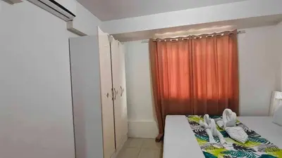 a bedroom with a bed and a orange curtain at 1148a 3br 1-king size 1queen size 2 double size 2-single size 1-extra matress Moa view in Manila
