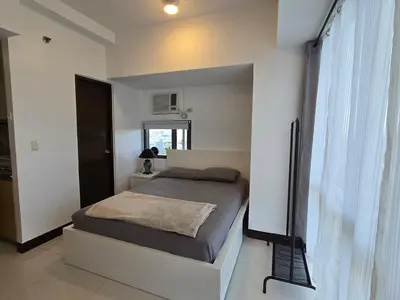 a bedroom with a bed in a white room at Cozy Corner Studio in McKinley Walk to Venice Mall in Manila
