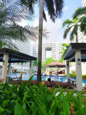 a resort with a pool and palm trees at Shell Residences MOA 2 beds by Dad's in Manila