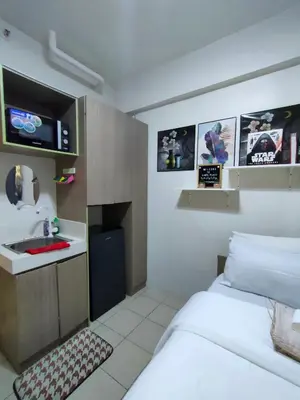 a small room with a bed and a sink at Trisha's Condotel Urban Deca Tower Edsa in Manila