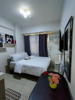 a bedroom with a bed and a table with flowers on it at Trisha's Condotel Urban Deca Tower Edsa in Manila