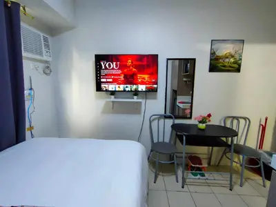 a room with a bed and a table and a tv at Trisha's Condotel Urban Deca Tower Edsa in Manila