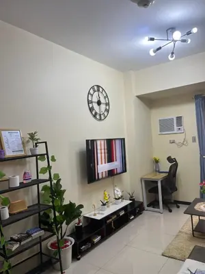 a living room with a clock on the wall at Bayfront Staycation at The Radiance Manila Pet-Friendly, Free Pool & Gym near Airport, MOA, Star City, Manila World Trade Center & Manila Bay in Manila