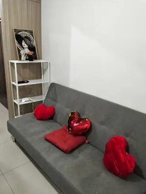 a gray couch with two red pillows on it at Ellein's Crib At Moa in Manila