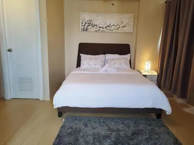 a bedroom with a large bed with white sheets at Condo Deluxe near NAIA Terminal 3 in Manila