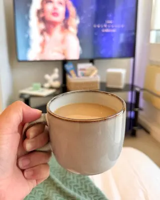 a person is holding a cup of coffee at Cozy Green 1 BR unit with Balcony Azure Bahamas South in Manila