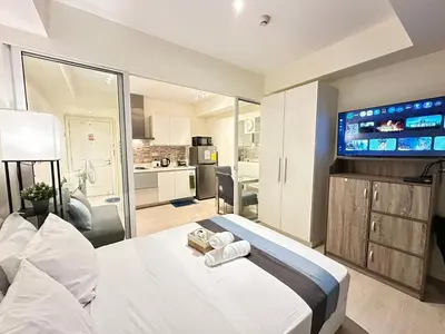 a bedroom with a large white bed with a flat screen tv at 1BR Condotel in Azure Urban Resort Near NAIA #BH1 in Manila